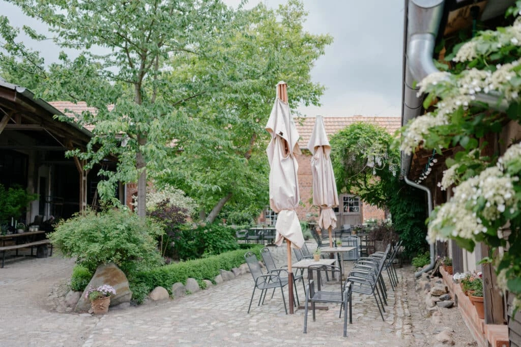 Rustikaler Innenhof mit Sitzplätzen und Sonnenschirmen.