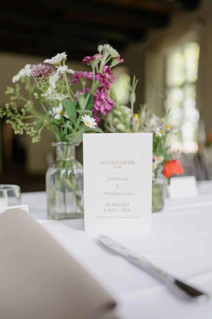 Menükarte und kleine Blumenvase auf der Hochzeitstafel.