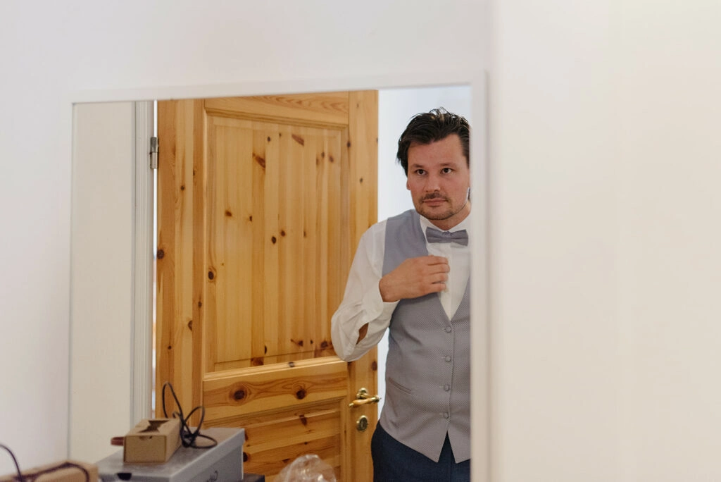 Bräutigam betrachtet sein Outfit im Spiegel.