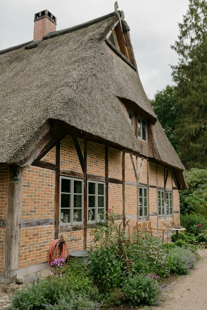 Reetgedecktes Fachwerkhaus mit blühendem Garten.