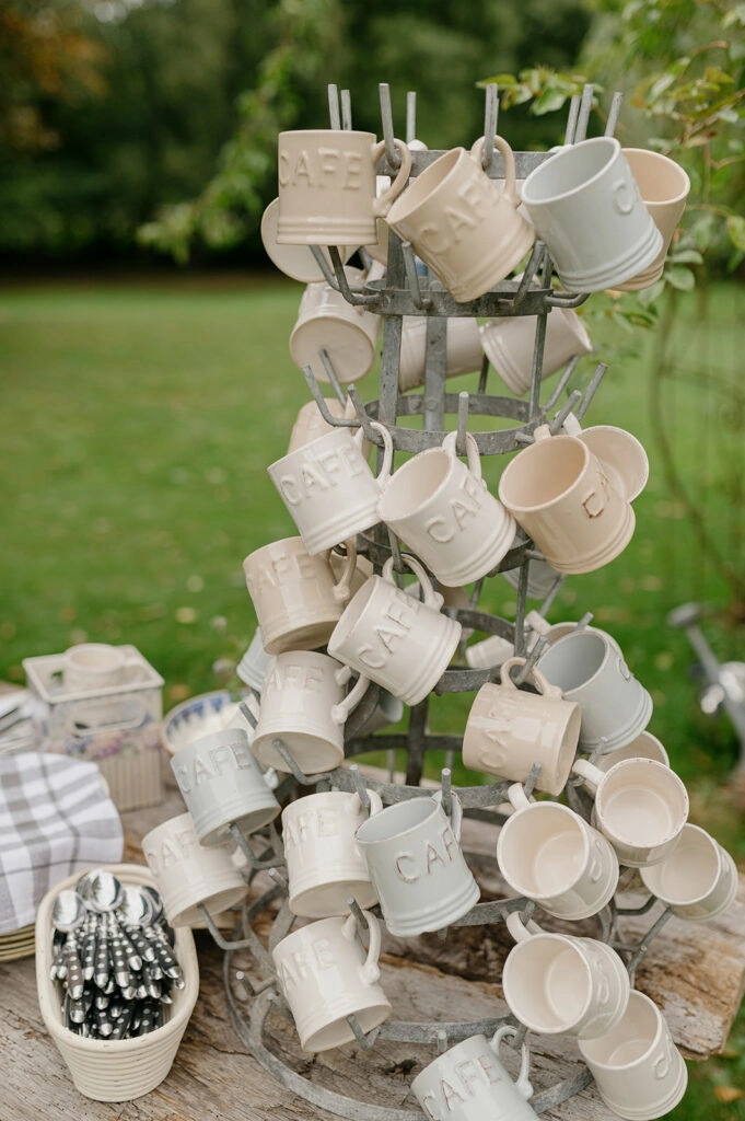 Viele weiße Kaffeetassen hängen an einem Tassenständer.