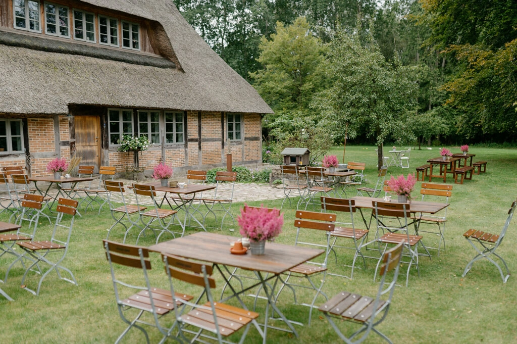 Gedeckte Gartentische vor dem Reetdachhaus.
