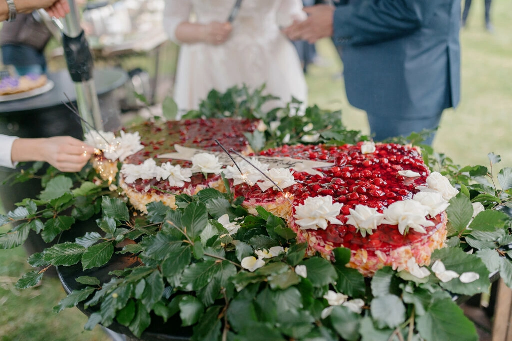 Herzförmige Hochzeitstorte mit roten Beeren und Blätterschmuck.