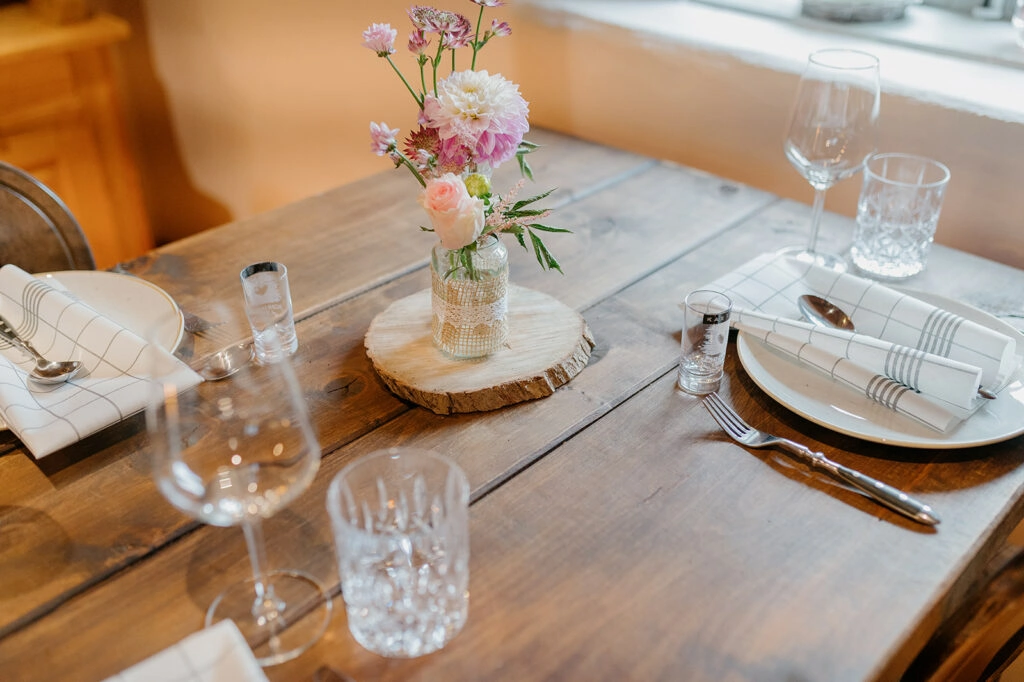 Gedeckter Platz mit Glasgeschirr und kleiner Blumenvase.