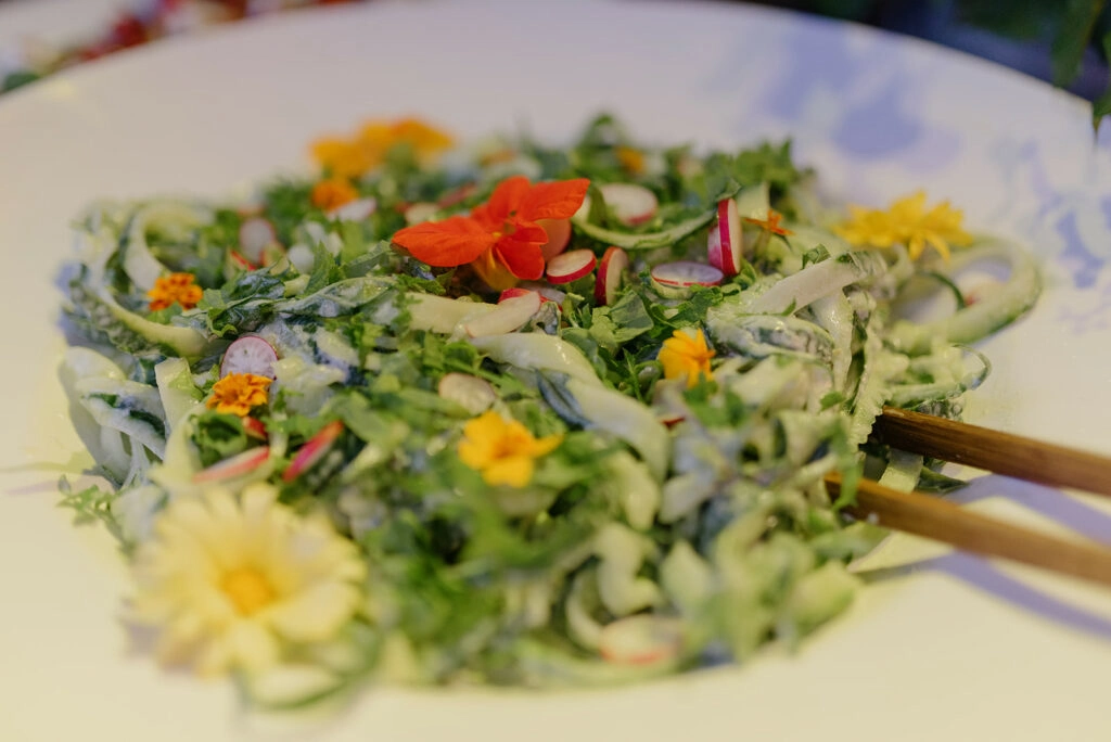 Grüner Salat mit essbaren Blüten auf einer Platte.