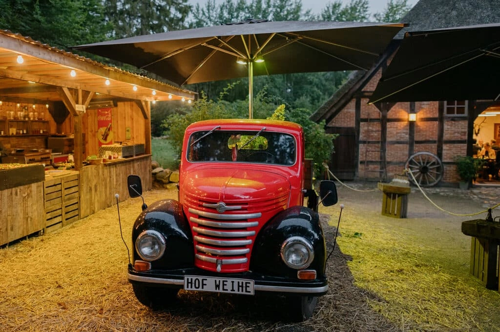 Roter Oldtimer vor der beleuchteten Hochzeitslocation am Abend.