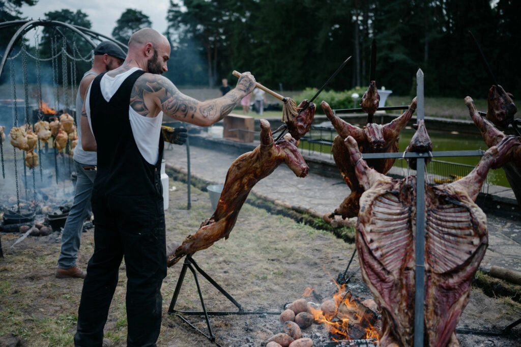 Fleisch wird an Gestellen über offenem Feuer gegart.