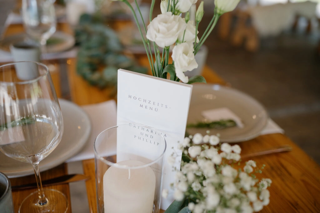 Menükarte und kleine Blumenvasen auf der Festtafel.
