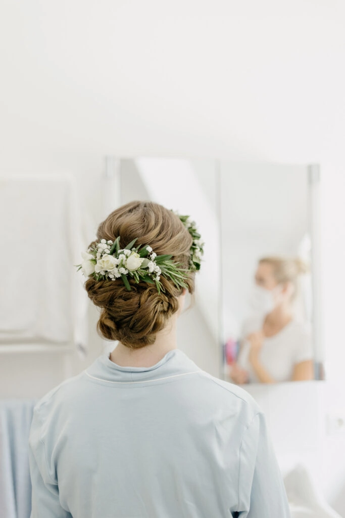Geflochtene Brautfrisur mit grünem Haarschmuck.