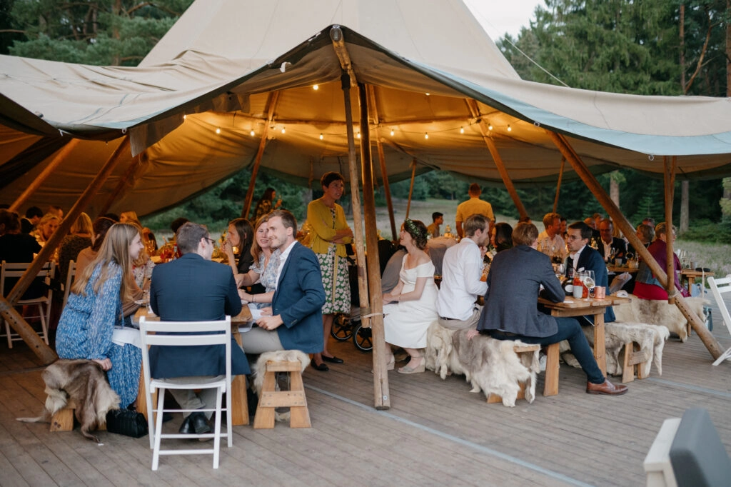 Gäste essen an den rustikalen Tafeln im Zelt.