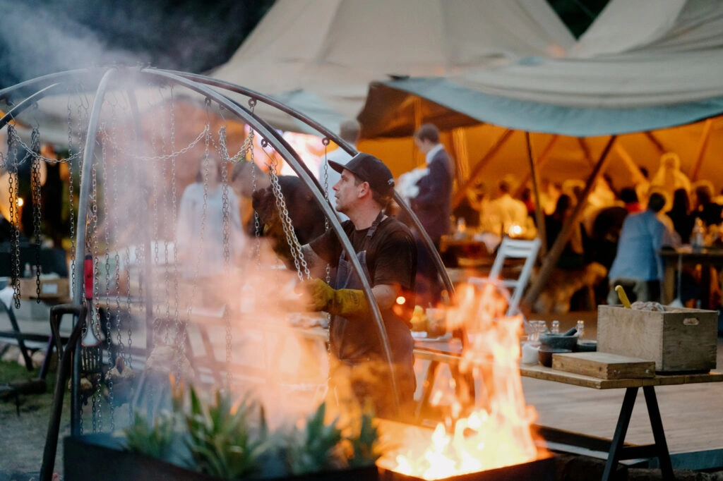 Feuerstelle vor dem beleuchteten Hochzeitszelt.