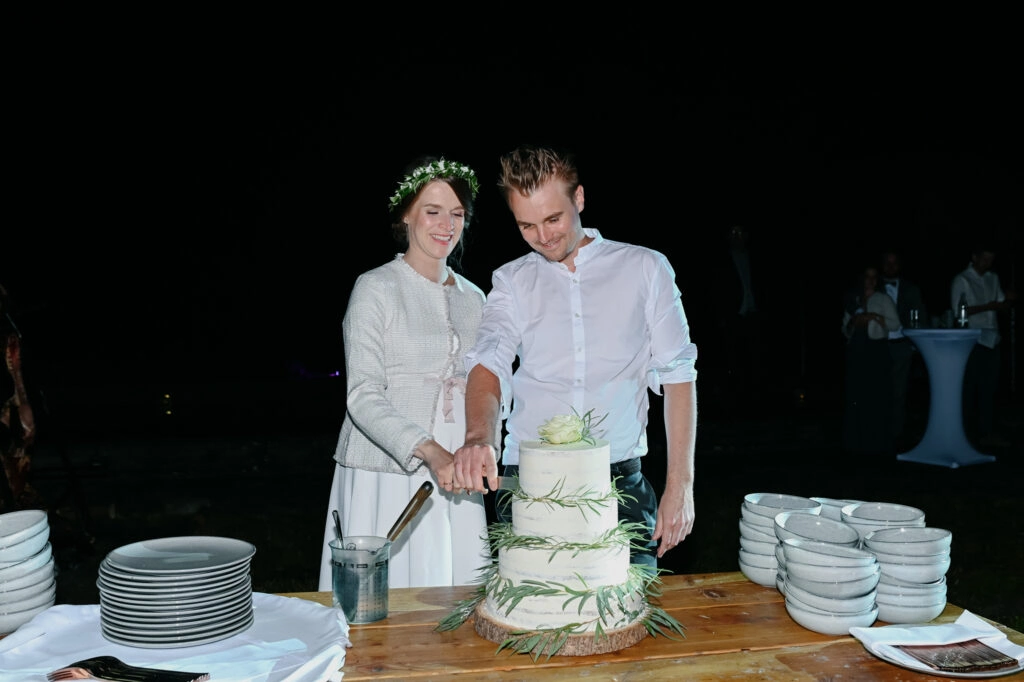 Brautpaar schneidet eine grün-weiße Hochzeitstorte an.