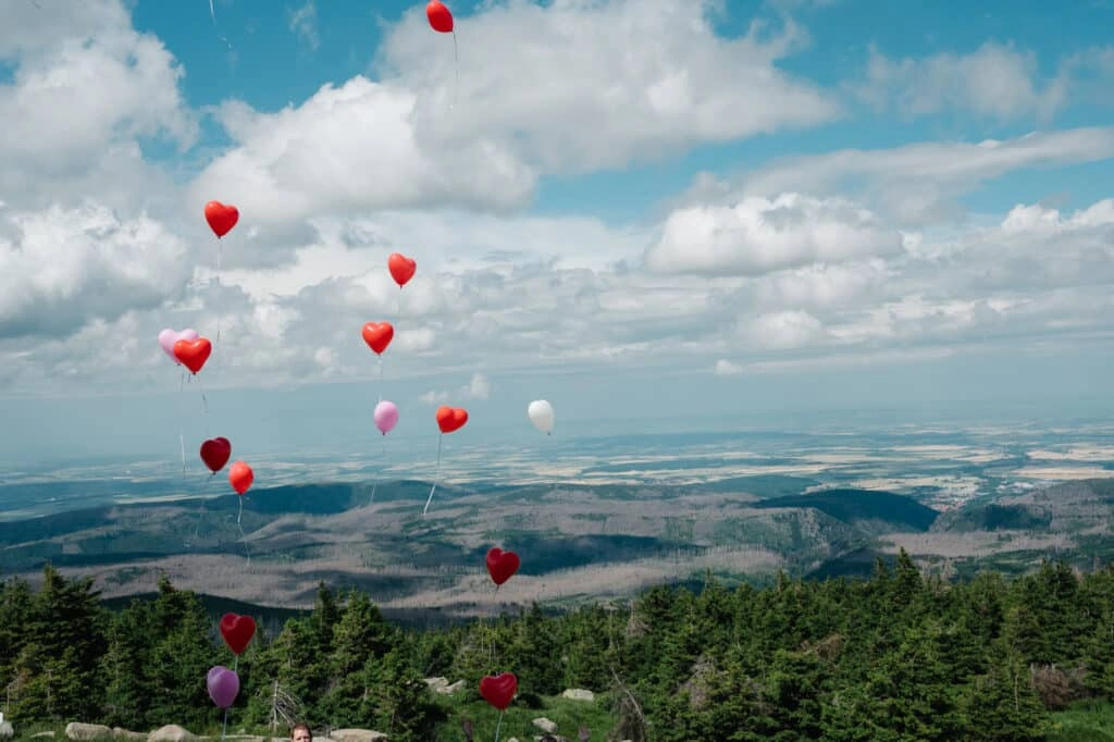 Herzförmige Luftballons steigen über der Berglandschaft auf.