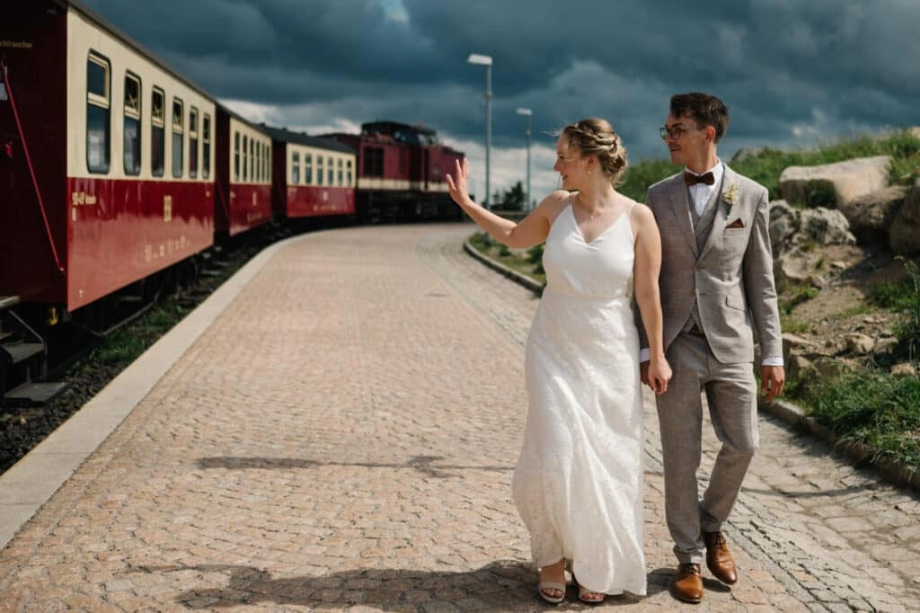 Brautpaar spaziert neben der roten Bahn über den Bahnsteig.