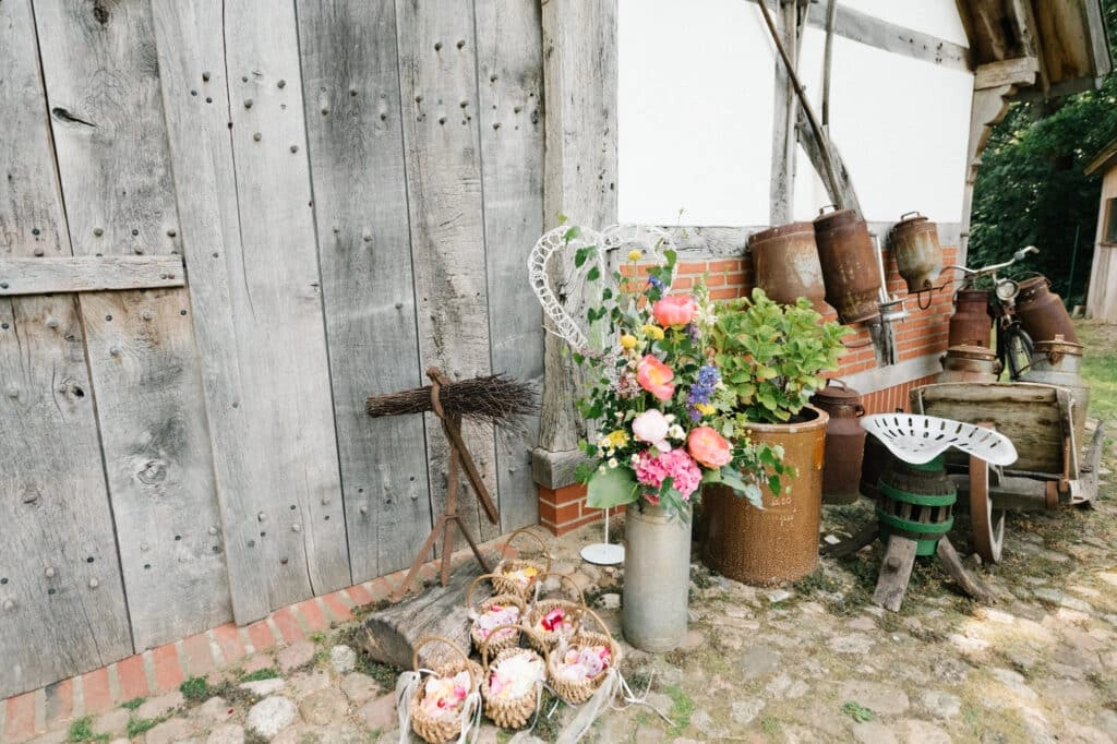 Blumen und alte Werkzeuge vor einem Holztor.