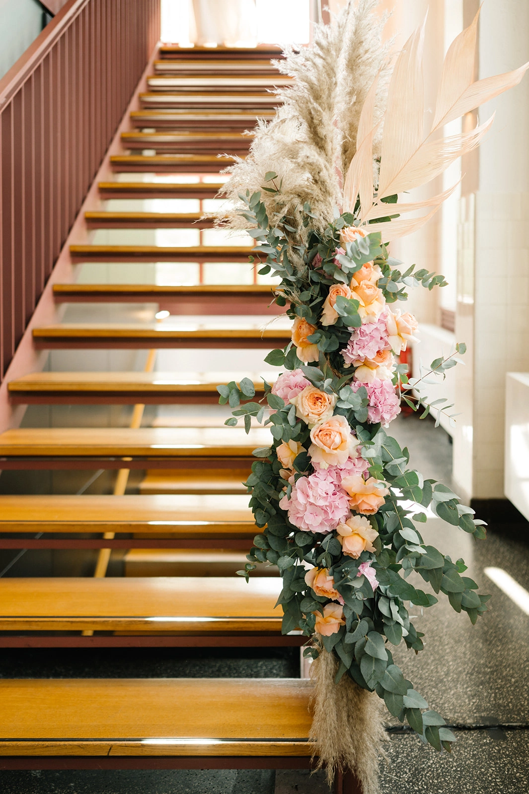 Treppe mit üppiger Blumen- und Pampasgrasdekoration.