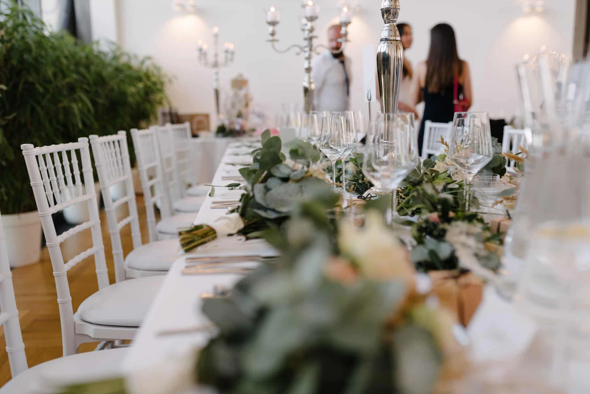 Lange Hochzeitstafel mit Eukalyptus und Kerzenleuchtern.