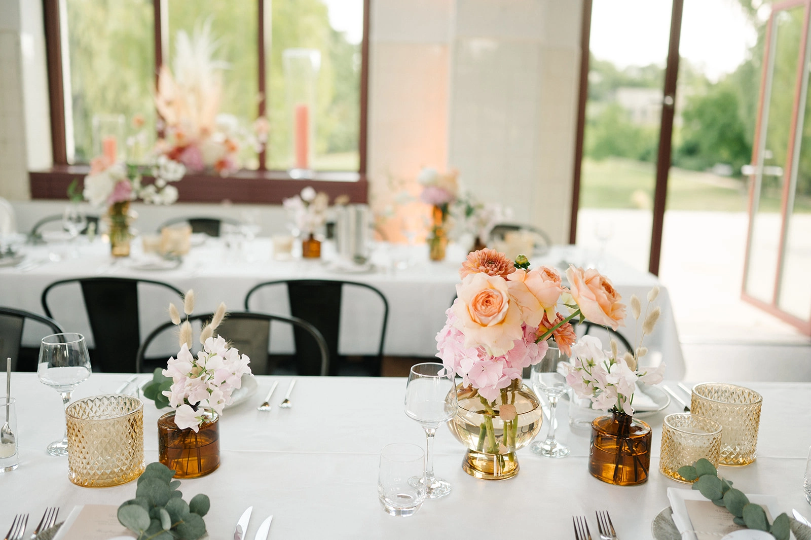 Hochzeitstische mit bunten Blumen im hellen Saal.