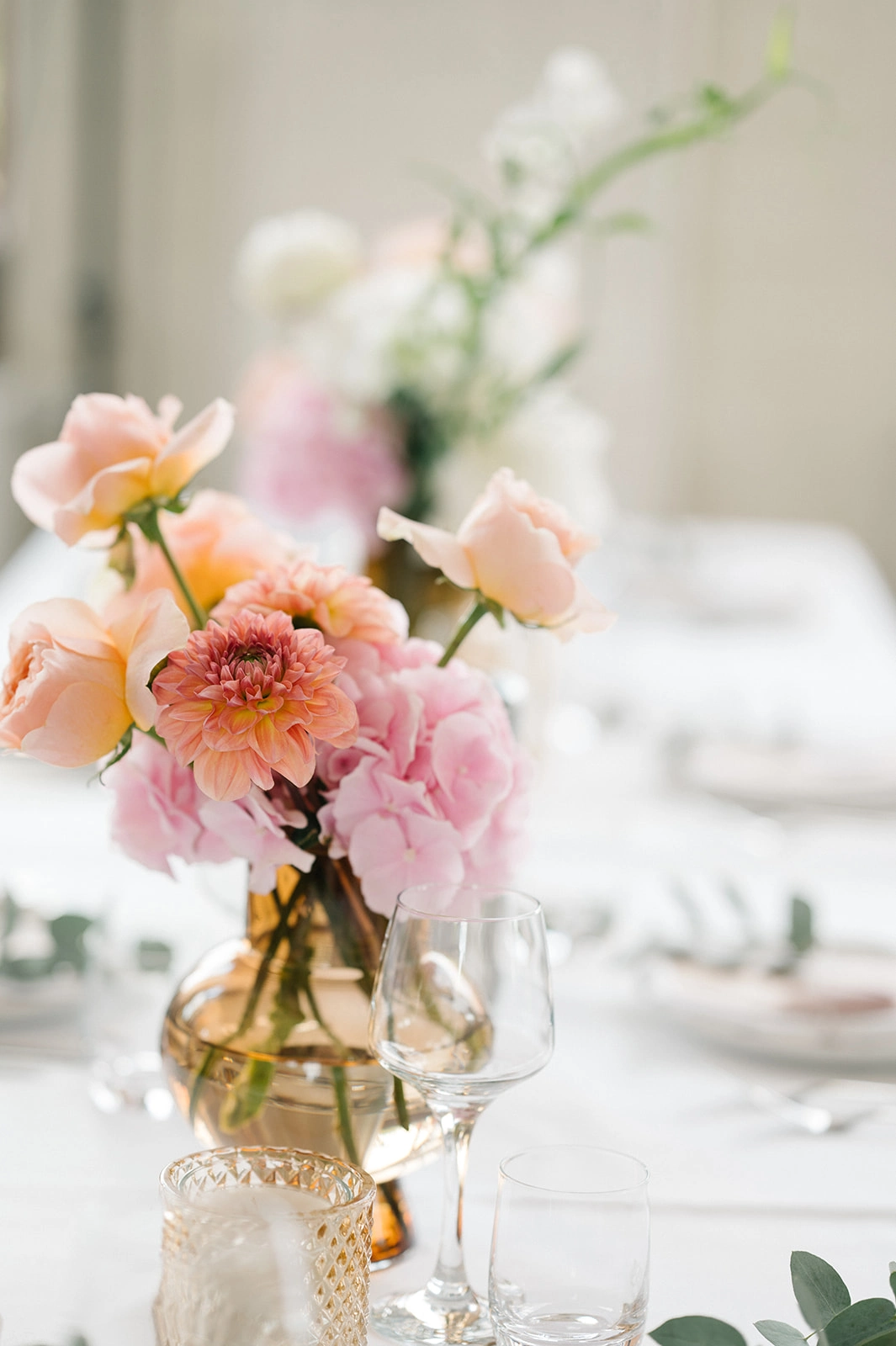Rosa und orange Blumen in einer kleinen Vase.