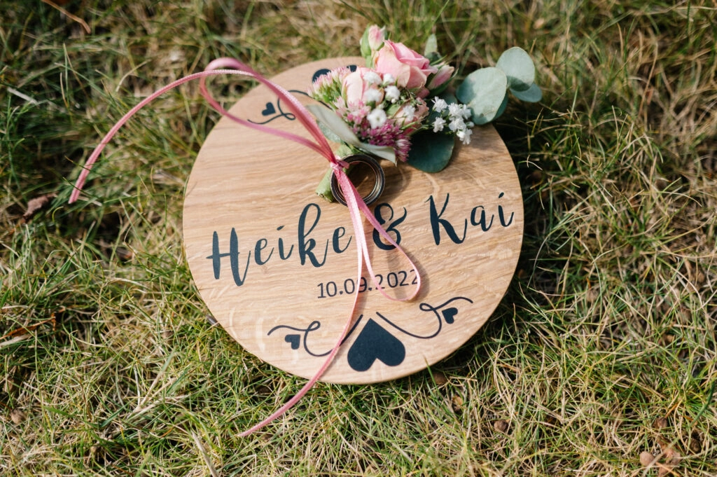 Holzschild mit den Namen Heike und Kai neben dem Brautstrauß.