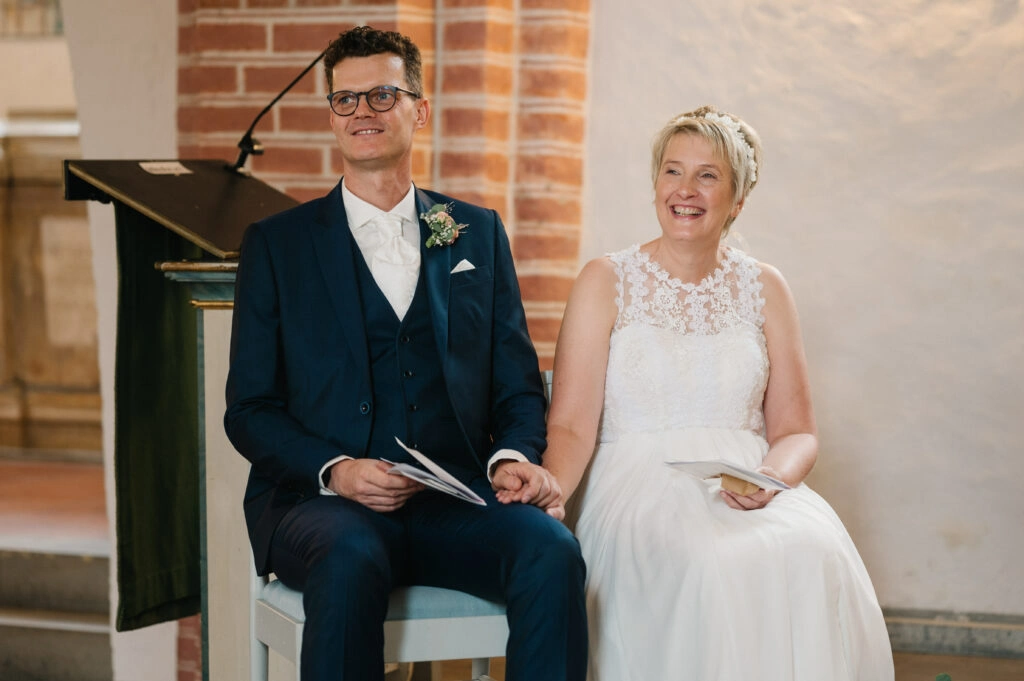Brautpaar sitzt während der kirchlichen Trauung vor dem Altar.