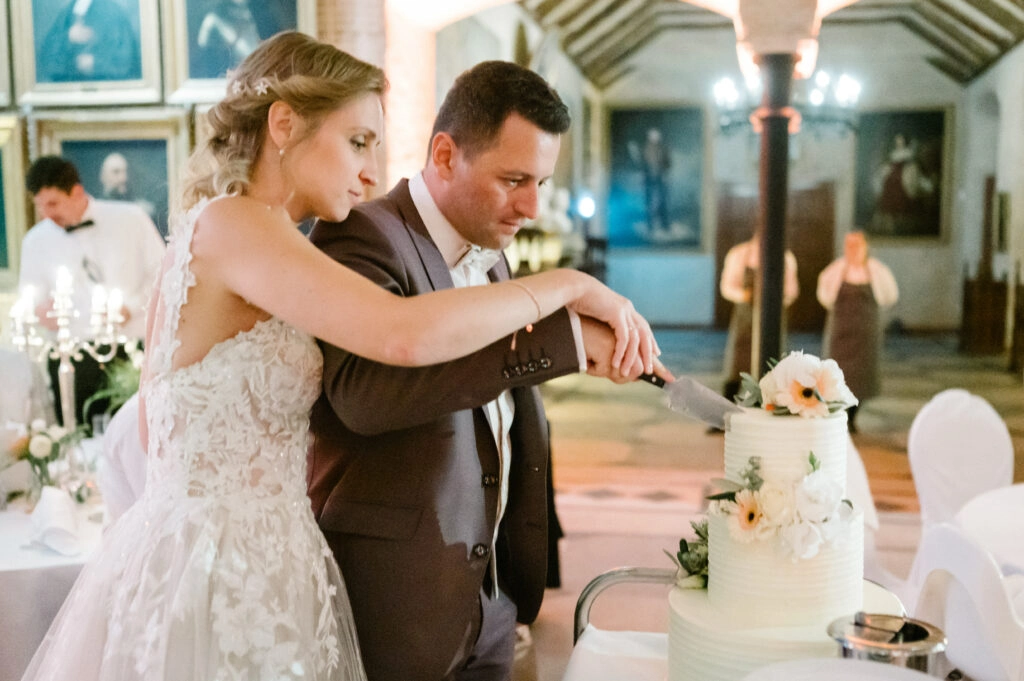 Brautpaar schneidet gemeinsam die Hochzeitstorte an.