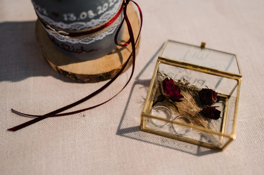 Eheringe in einer kleinen Glasbox mit getrockneten Blüten.