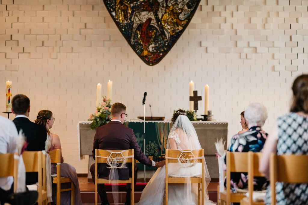 Brautpaar sitzt vor dem Altar während der kirchlichen Trauung.