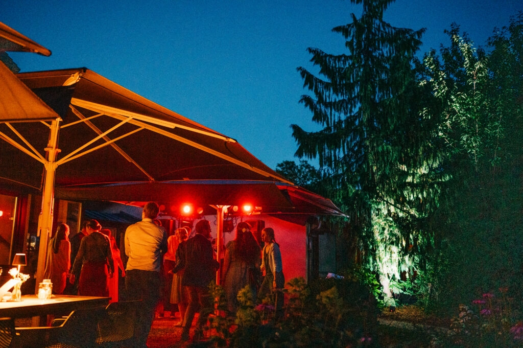 Hochzeitsfeier auf einer beleuchteten Terrasse in der Dämmerung.