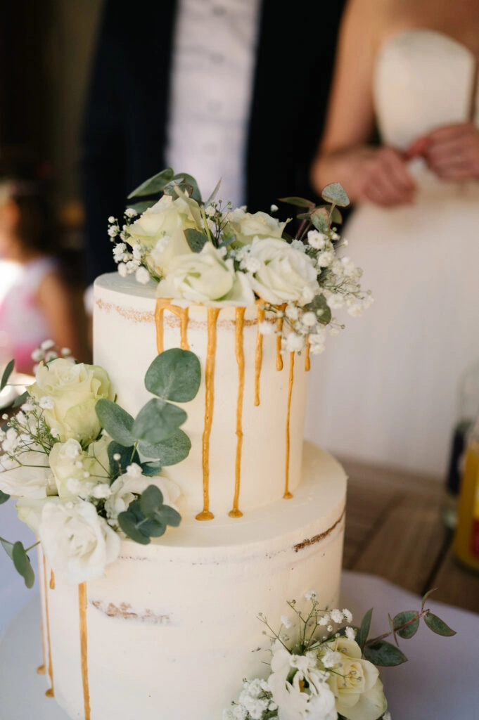 Mehrstöckige Hochzeitstorte mit Blumen und goldenen Verzierungen.