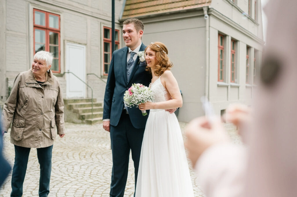 Brautpaar posiert mit einem Gast im Freien.
