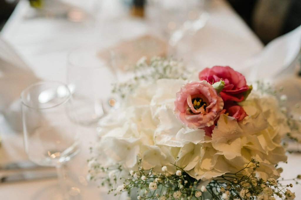 Rosa und weiße Blumen auf der Hochzeitstafel.