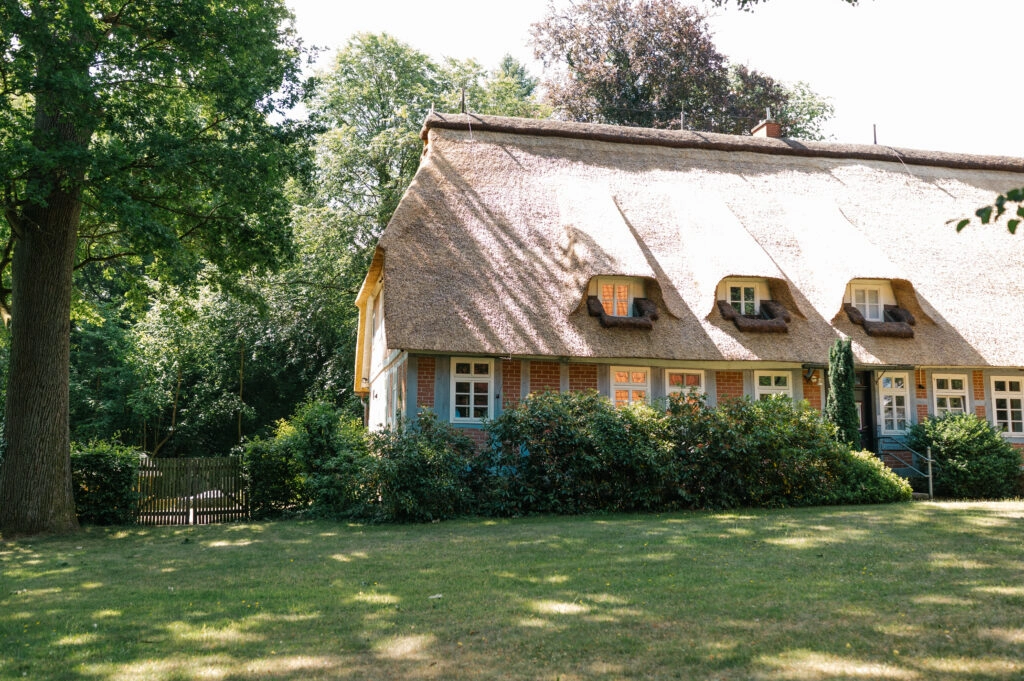 Reetgedecktes Haus in einem grünen Garten.