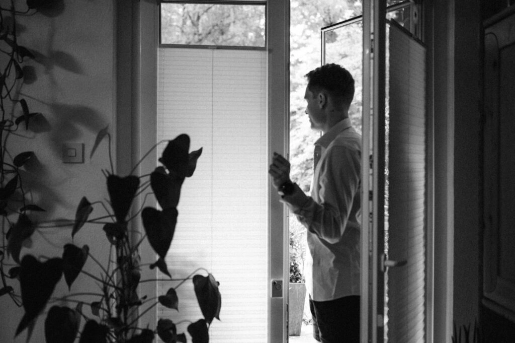 Bräutigam bereitet sich am Fenster vor, in Schwarz-Weiß.