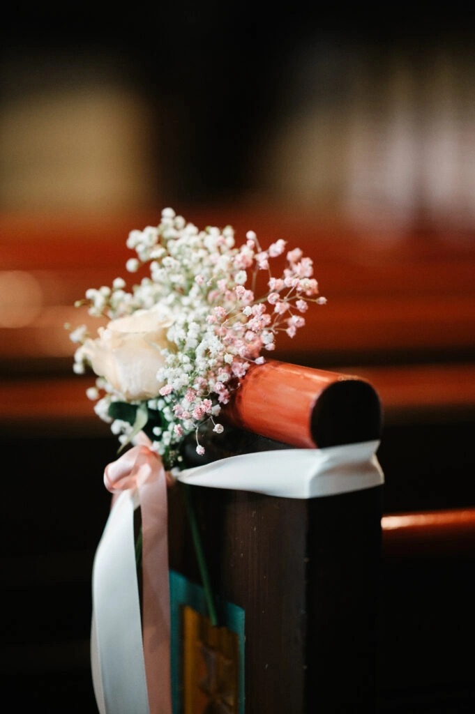 Blumen und Schleifen an einer Kirchenbank.