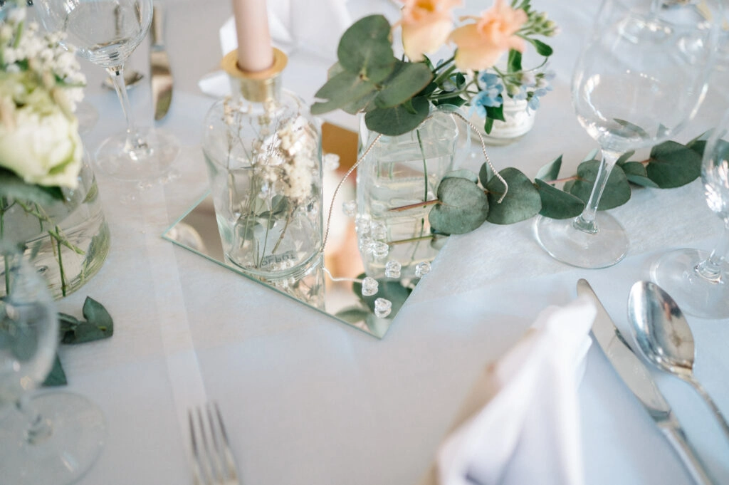 Hochzeitstisch mit Blumen, Eukalyptus und Kerzen.
