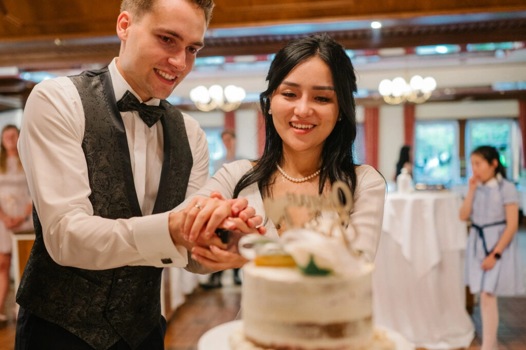 Brautpaar schneidet gemeinsam die Hochzeitstorte an.