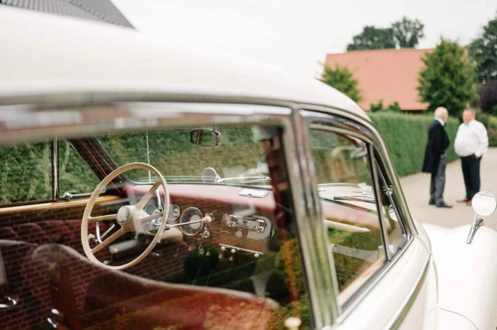 Blick durch das Fenster auf das Lenkrad eines weißen Oldtimers.