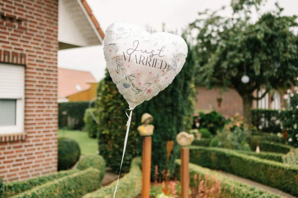 Herzförmiger Just-Married-Ballon vor dem Backsteinhaus.