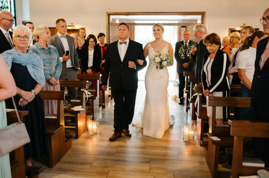 Braut wird durch den Mittelgang in die Kirche begleitet.