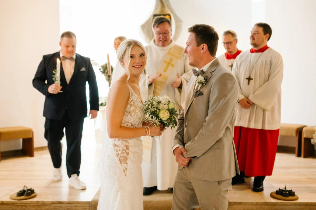 Brautpaar steht mit Begleitern vor dem Altar.
