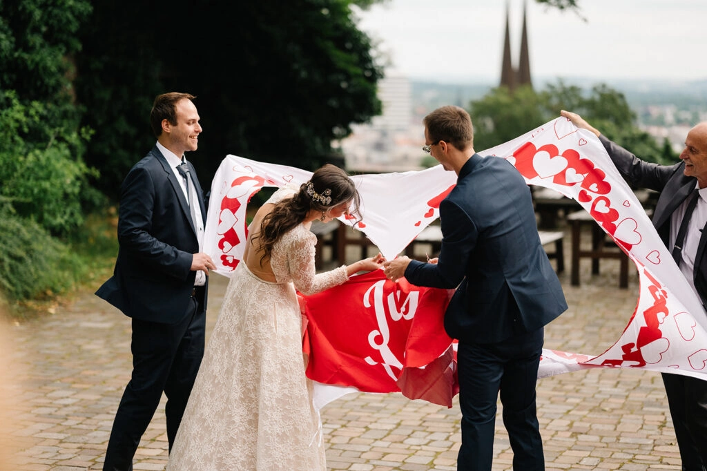 Brautpaar steigt durch ein ausgeschnittenes Herz im Hochzeitstuch.