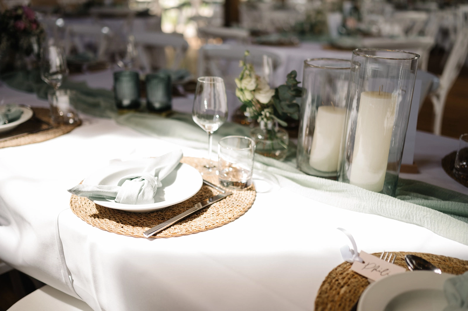 Gedeckter Hochzeitstisch mit Kerzen und geflochtenen Platztellern.
