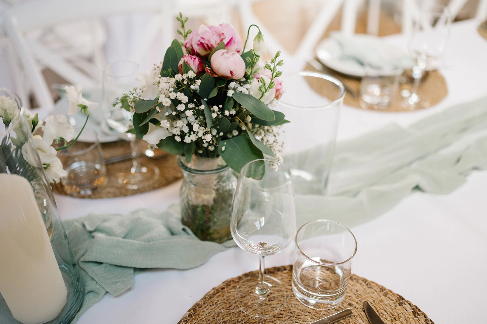 Rosa Blumen und grüne Tischläufer auf der Hochzeitstafel.