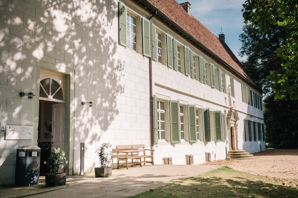 Historisches Gebäude mit hellen Wänden und grünen Fensterläden.