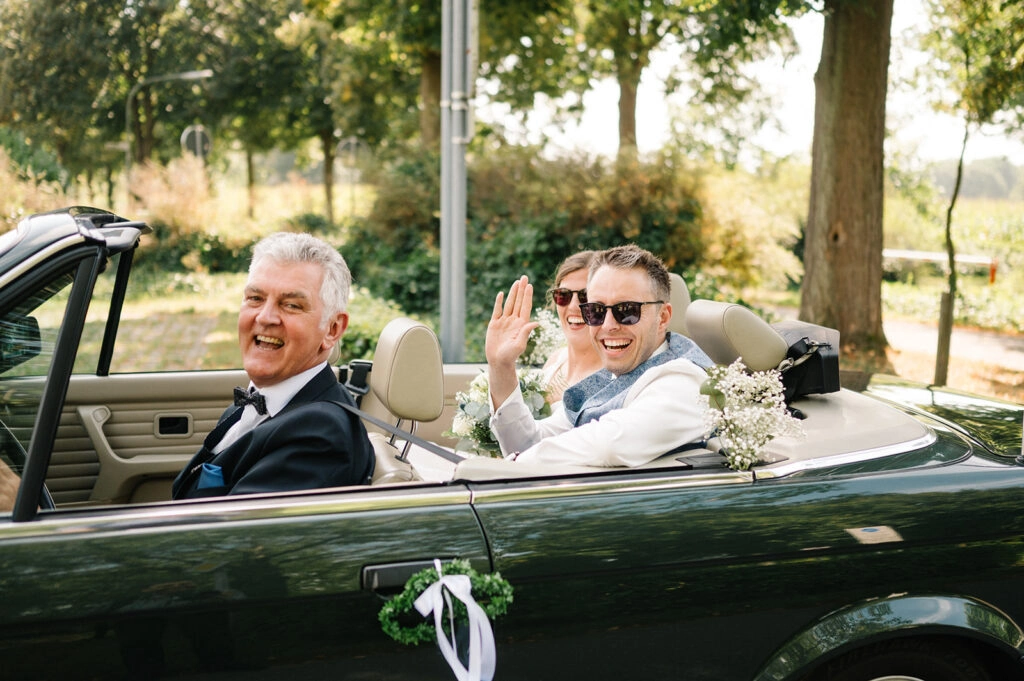 Bräutigam und Begleiter im offenen Hochzeitsauto.