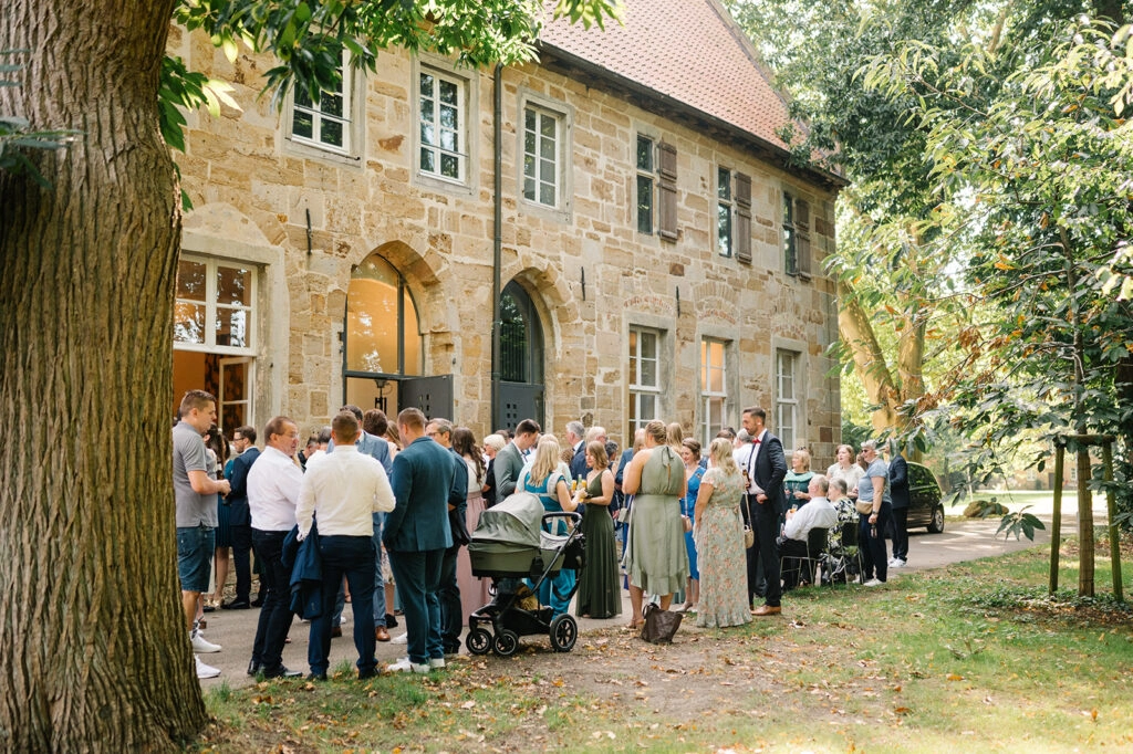 Hochzeitsgesellschaft vor dem historischen Gebäude.