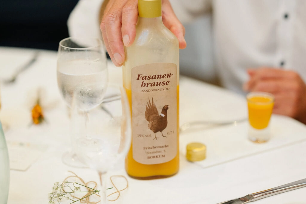 Eine Flasche wird auf den Hochzeitstisch gestellt.