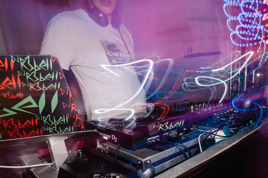 DJ am Mischpult bei buntem Partylicht.