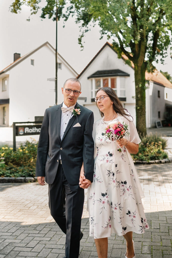 Brautpaar geht Hand in Hand zum Standesamt.